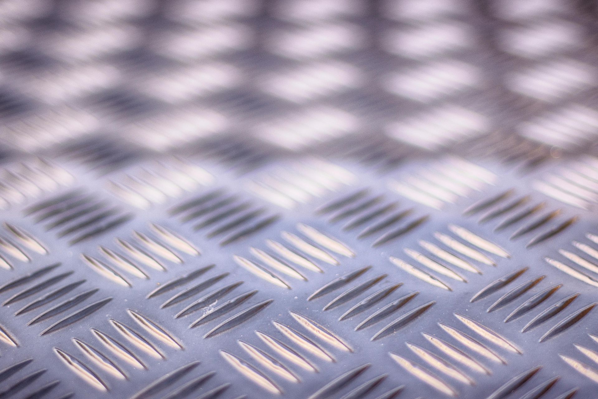Close-up of silver diamond-plate metal with textured, reflective pattern