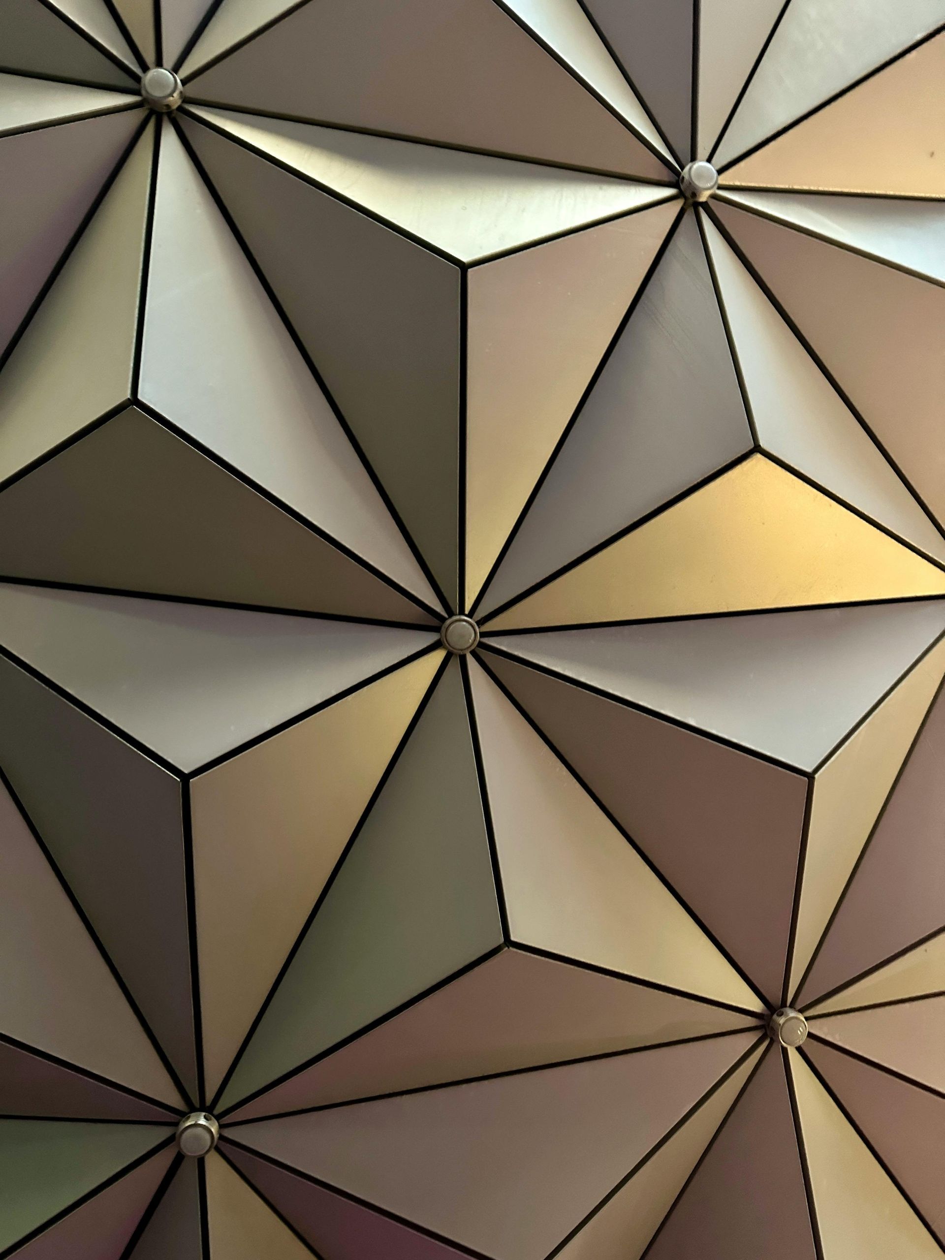 Abstract geometric pattern of faceted triangles in beige, gray, brown, and pale yellow tones