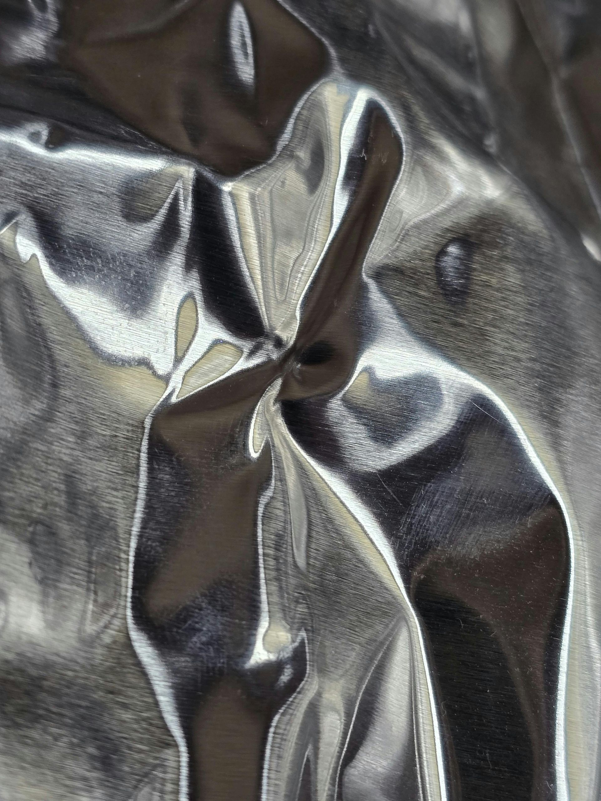 Shiny crumpled silver and black satin fabric with abstract folds and highlights