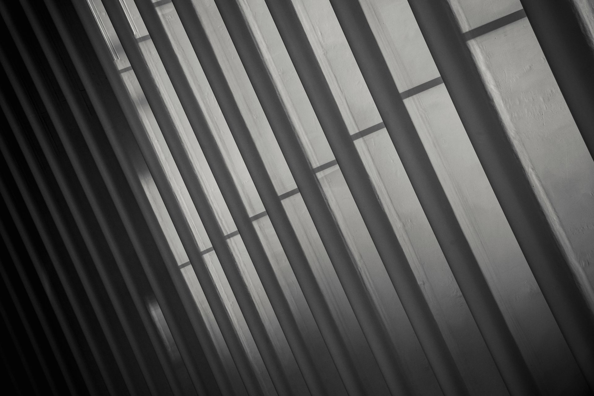 Diagonal black-and-white close-up of vertical metal bars casting strong shadows