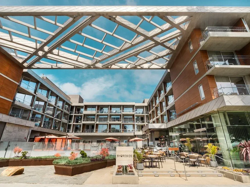 Modern hotel courtyard with outdoor seating, planters, and a glass canopy overhead