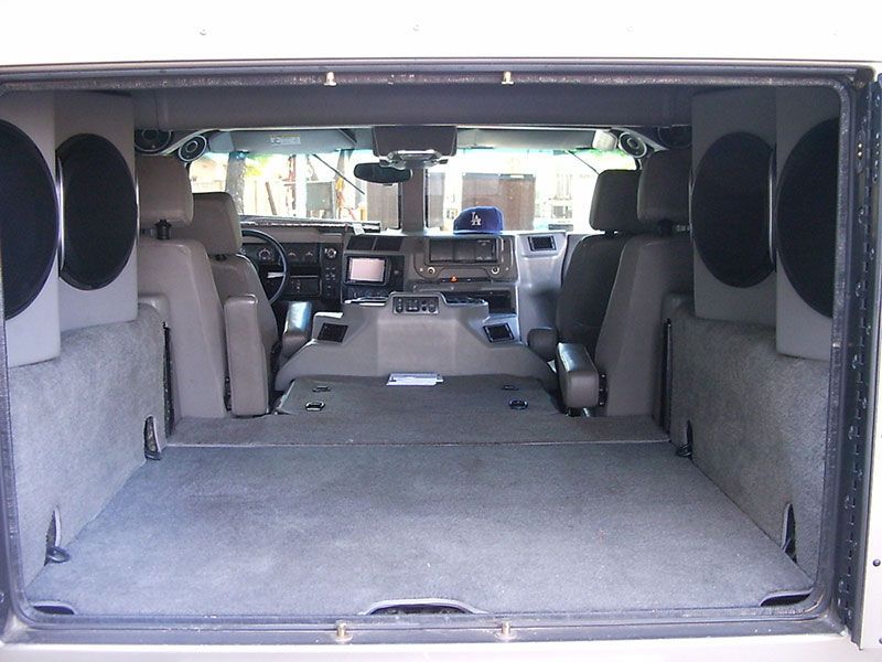 Open SUV cargo area with rear seats folded flat, showing gray carpet and interior speakers.