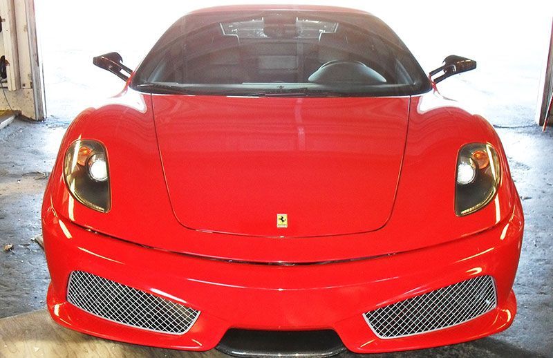 Front view of a red sports car parked indoors, centered in a garage.