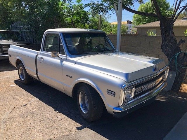 Classic white pickup truck parked outdoors in sunlight, viewed from the front-left side.