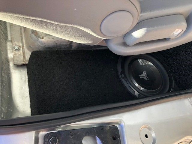Car trunk with a subwoofer speaker installed beside the rear seat.