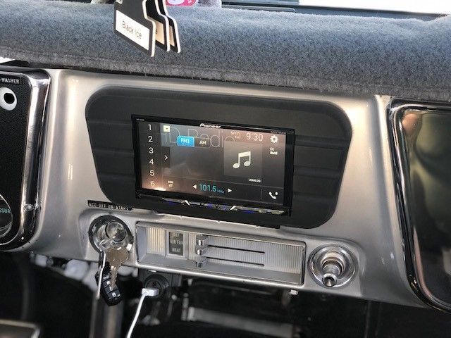 Car dashboard with a central touchscreen displaying music controls and silver climate knobs.