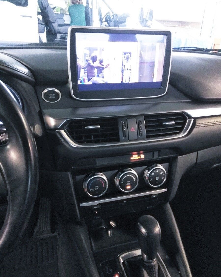 Car dashboard with center touchscreen, air vents, climate controls, and gear shift visible