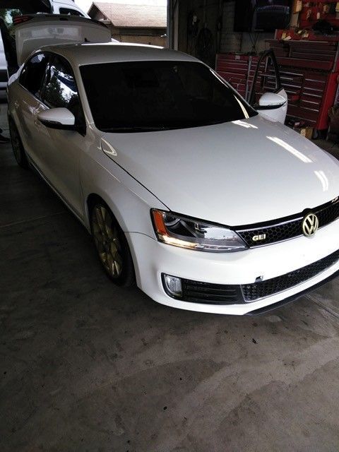 White Volkswagen hatchback parked in a garage, viewed from the front-left.