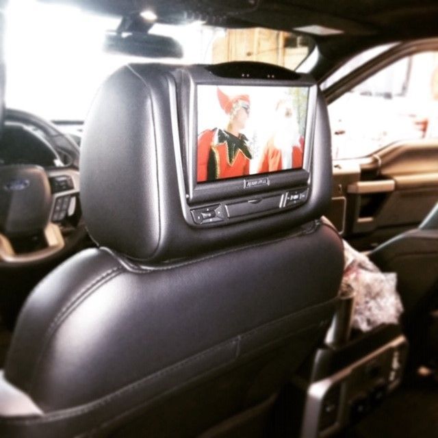 Car seat headrest with a built-in screen playing a video in a car interior