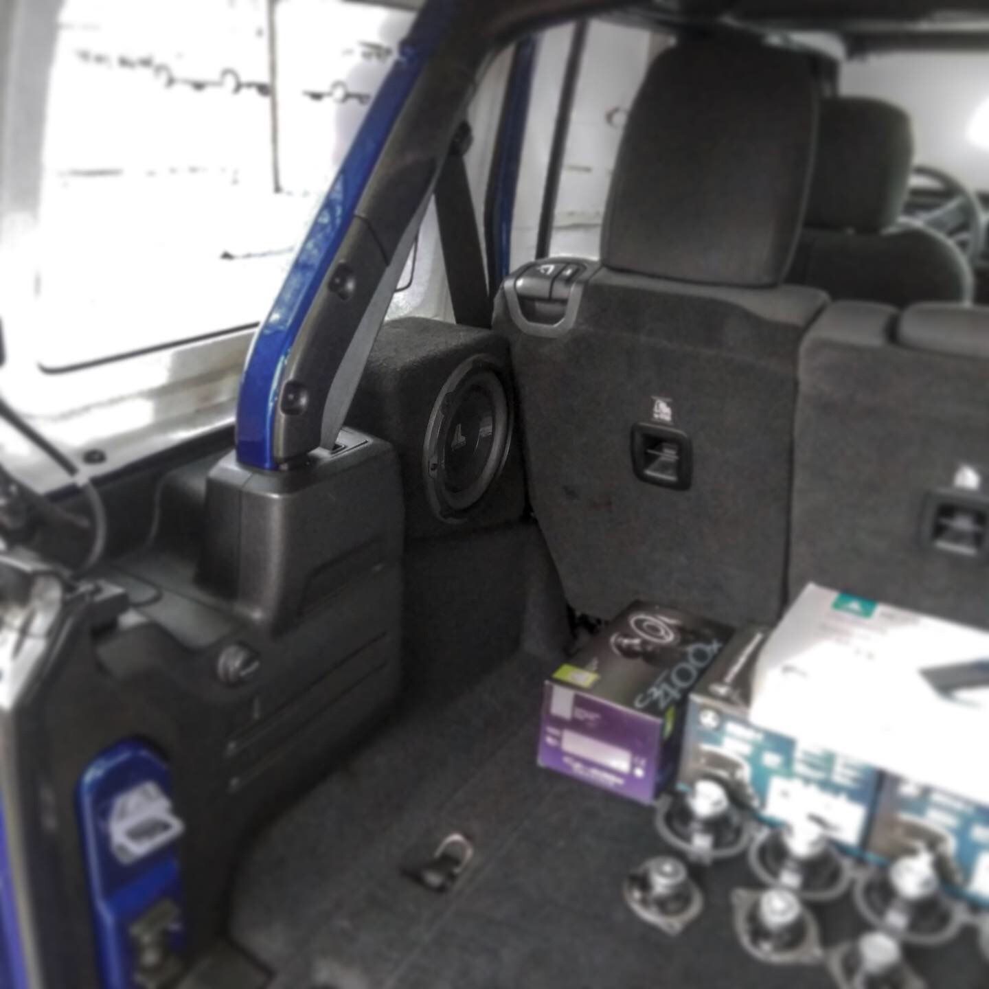 Car interior with folded seats, blue roll bar, and scattered equipment in the cargo area.