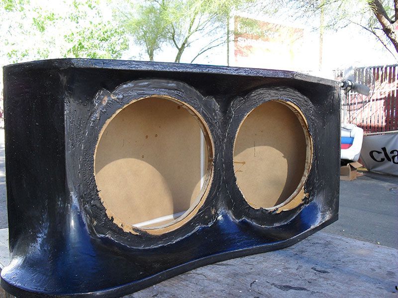 Black dual-speaker cabinet with two large circular cutouts outdoors.