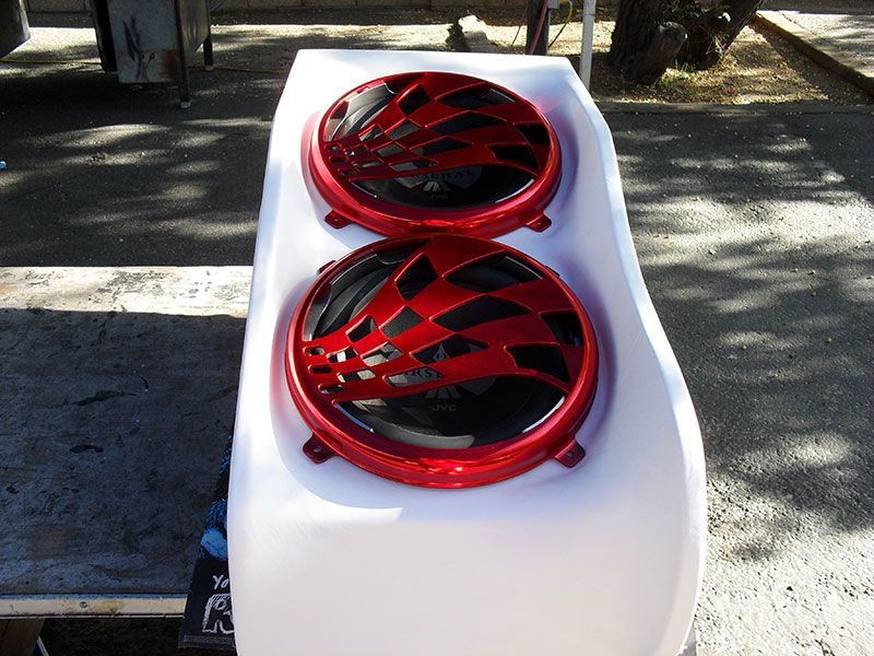 Two red-and-black racing wheel rims on a white surface outdoors