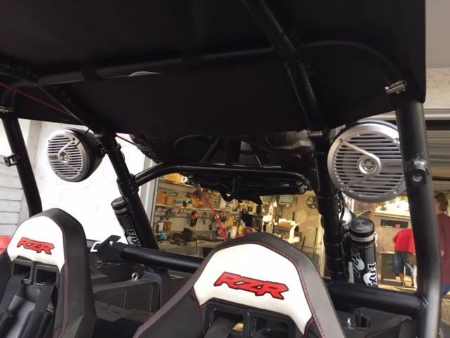 Interior of an off-road vehicle with white bucket seats and a visible rear engine, viewed from the back.