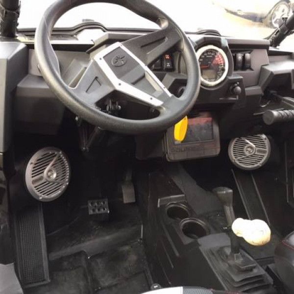 Spartan off-road vehicle interior with steering wheel, gauges, pedals, and a center console with a gear lever.