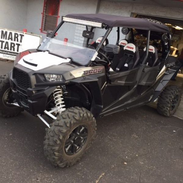 Black off-road UTV with roll cage and knobby tires parked outside a store
