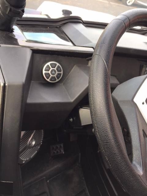 Close-up of a car interior dashboard and steering wheel with a small circular speaker or vent.