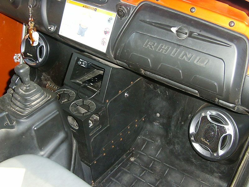 Interior of a vehicle with a black dashboard, gear shifter, and round speaker/vent on the passenger side.