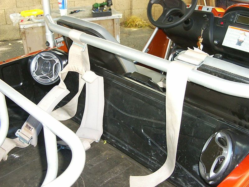 White roll cage and racing seat in a car interior with detached steering wheel and dashboard parts