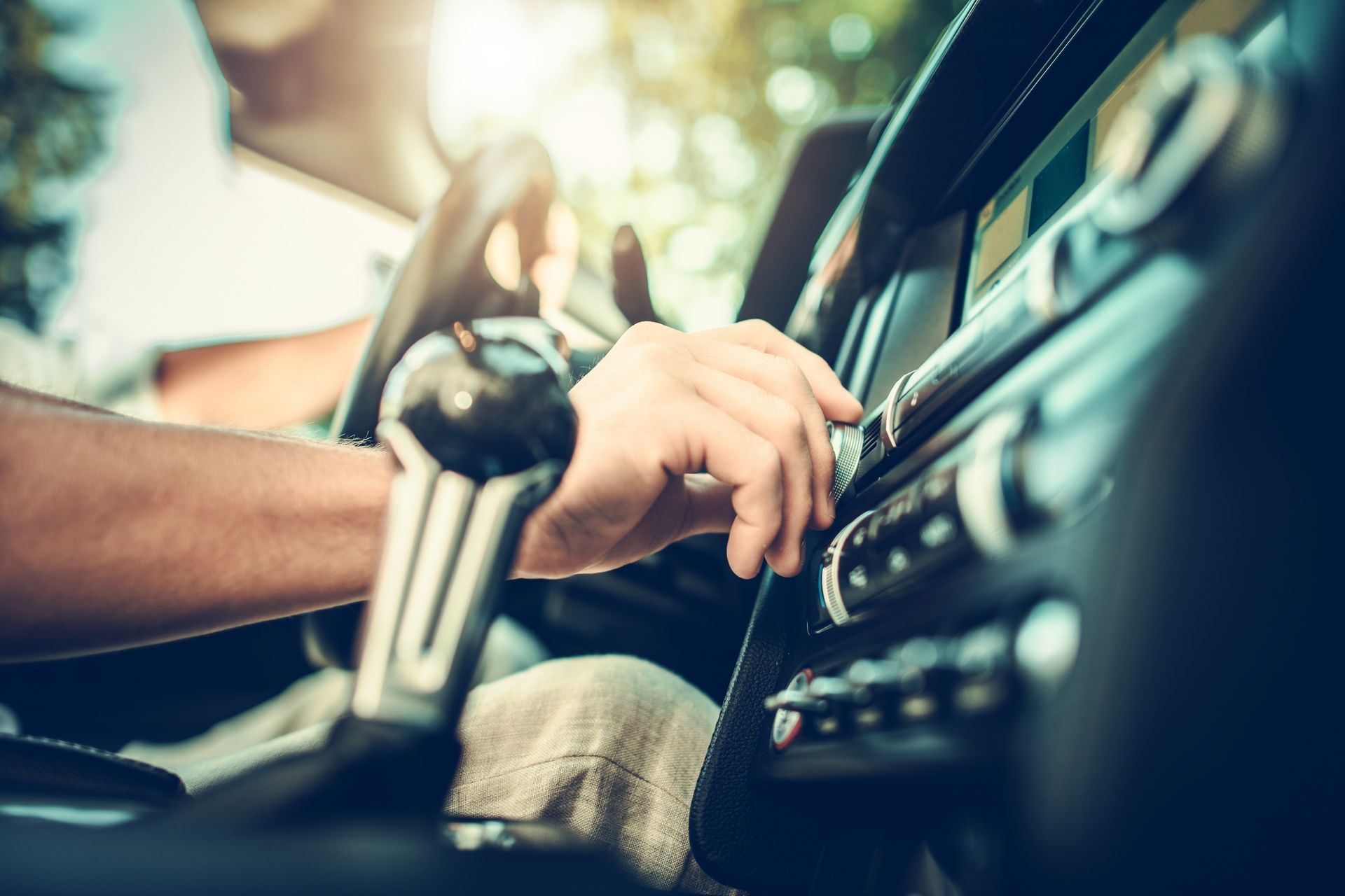 Hand adjusting the controls on a car stereo inside a vehicle.