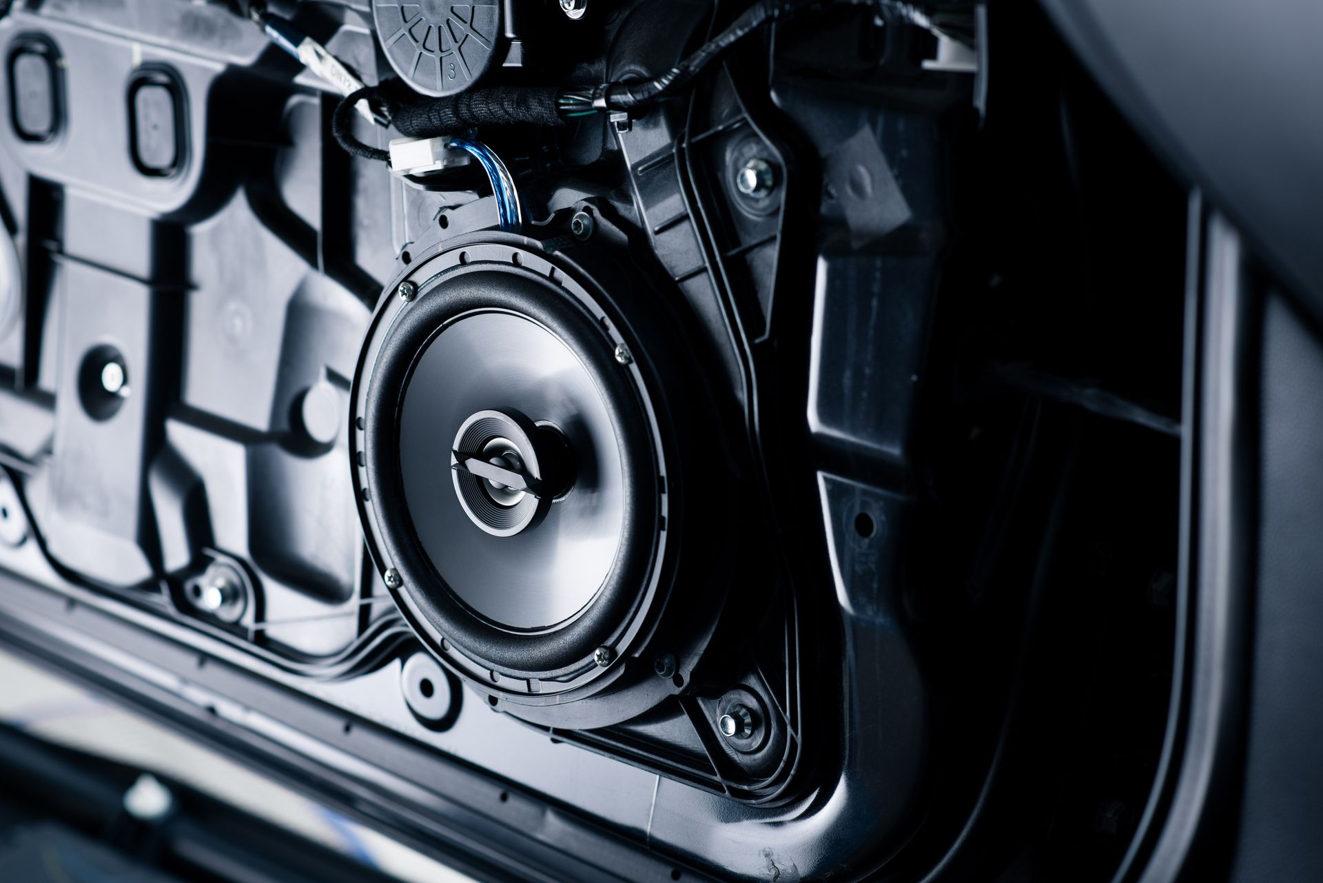 Close-up of a metallic car engine component with a circular valve or speaker-like part in a dark mechanical housing