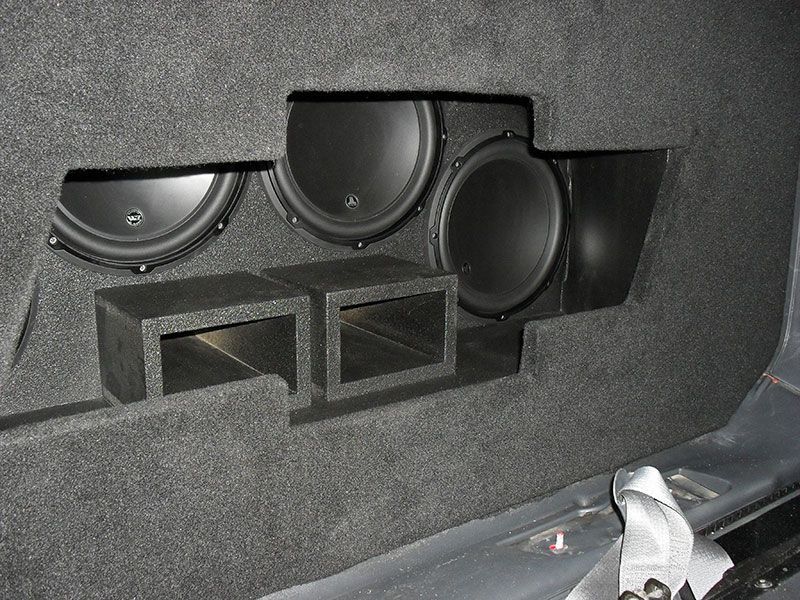 Car audio subwoofer enclosure with multiple speakers mounted in a black carpeted trunk panel