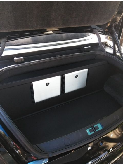 Open car trunk with black interior and two white storage boxes inside.