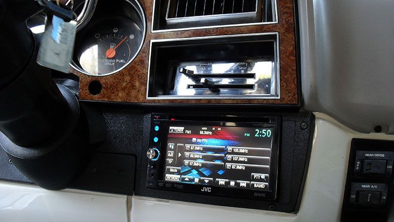 Car dashboard with an aftermarket stereo, gauge cluster, and center console controls.