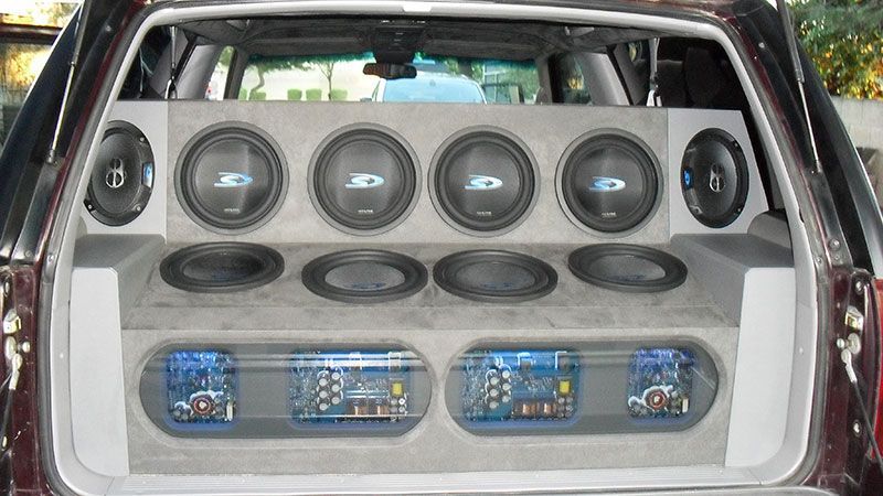 Car trunk filled with a custom speaker system and blue-lit audio components