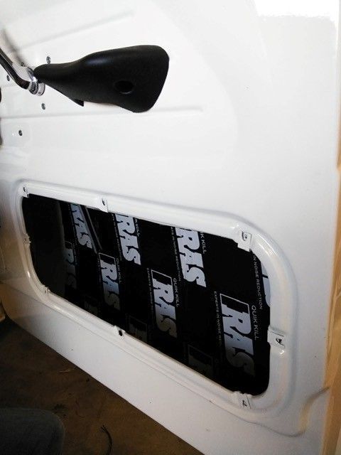 White car door with a black side mirror and an open panel showing black insulation inside.