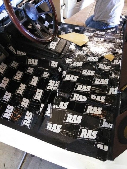 Black race car chassis with RLS-branded flooring and a person working inside the cockpit area