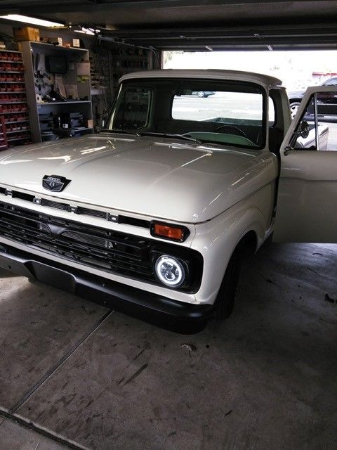 White vintage pickup truck parked in a dim garage, front-left view with the driver door open