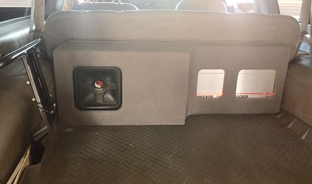 Gray vehicle interior with a small storage panel and two vents on a black floor mat.