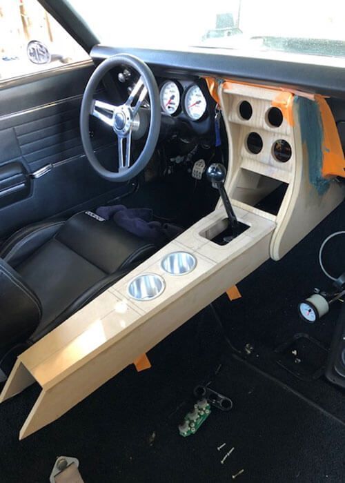 Custom car interior with tan center console, three gauges, and a black steering wheel