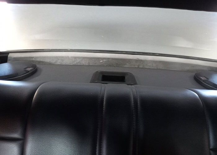 Back seat of a car with black leather upholstery and rear window ledge visible