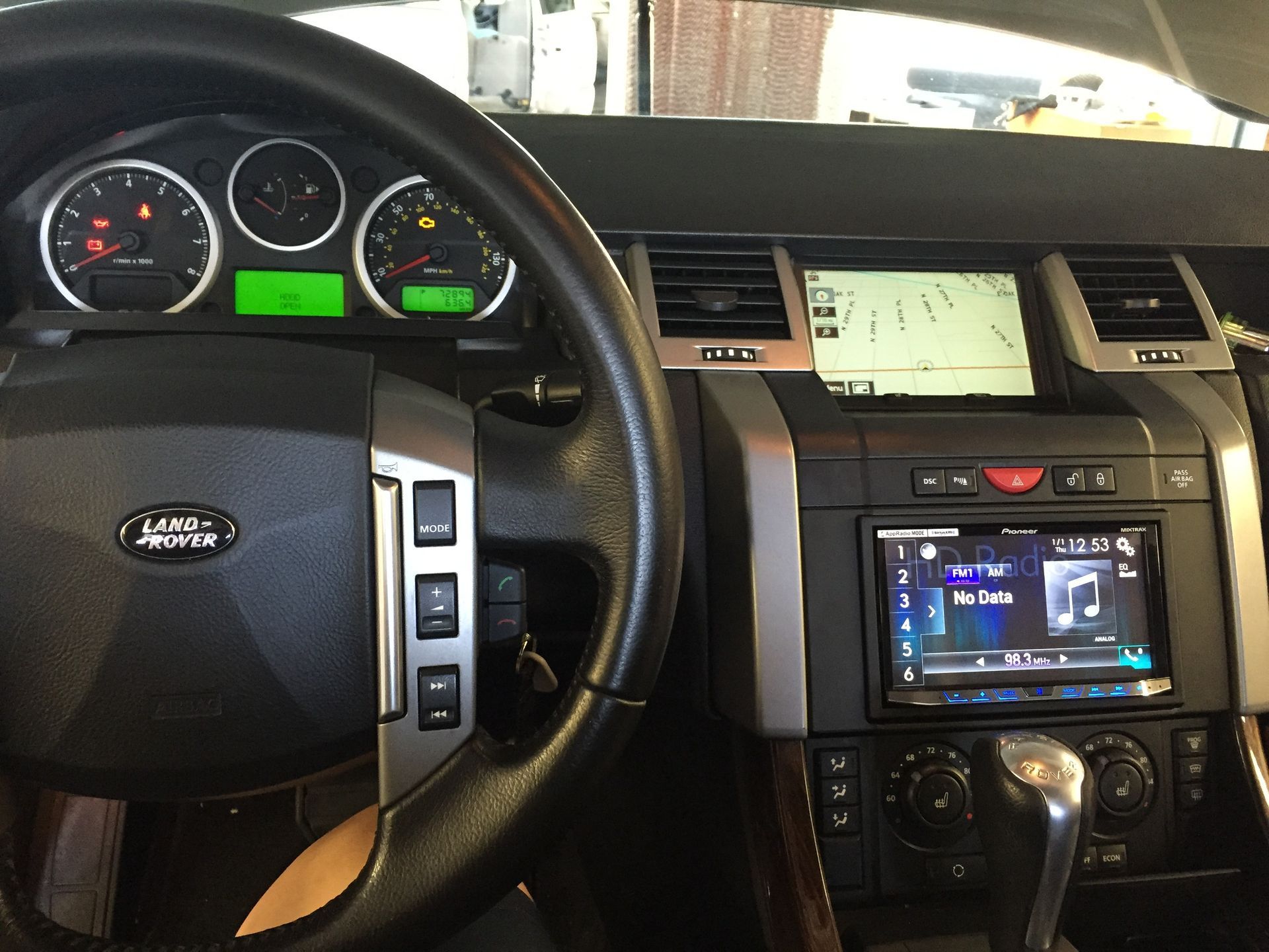 Car dashboard and center console with steering wheel, gauges, touchscreen, and gear shift.