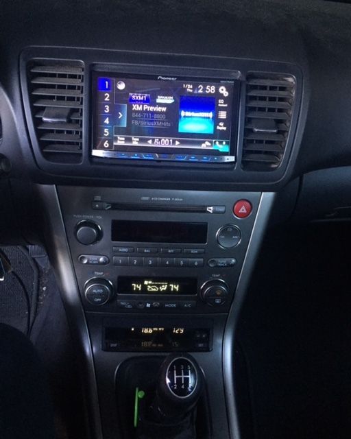 Car center console with touchscreen radio, climate controls, hazard button, and manual gear shift