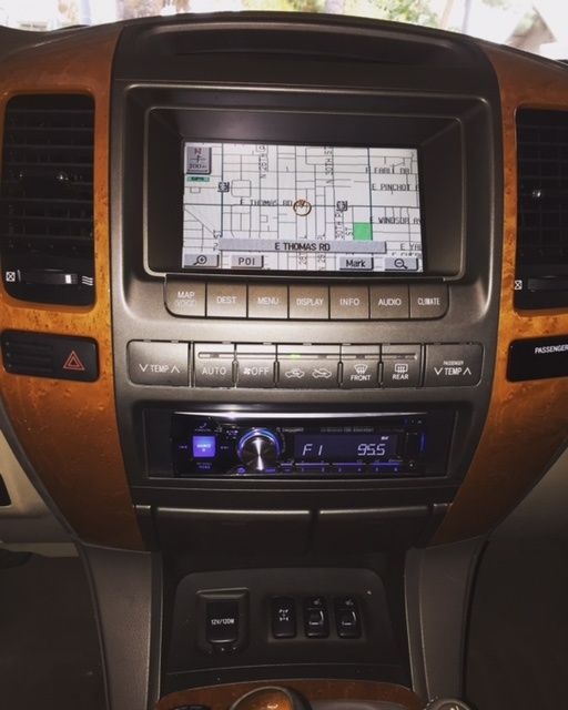Car dashboard center console with GPS screen, wood trim, buttons, and blue-lit stereo display