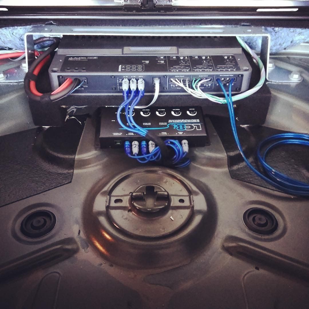 Car stereo amplifier setup with blue wiring mounted in a vehicle trunk