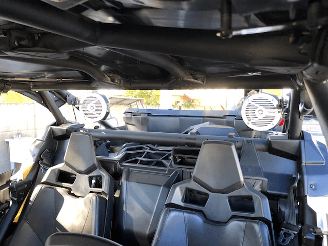 Interior of an off-road buggy with two black bucket seats and roll cage, viewed from the rear.