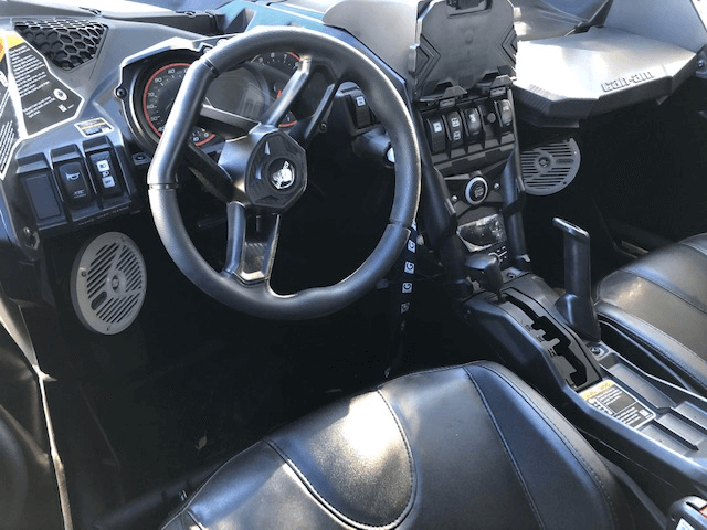 Car interior with black leather seats, steering wheel, dashboard controls, and silver speaker grilles