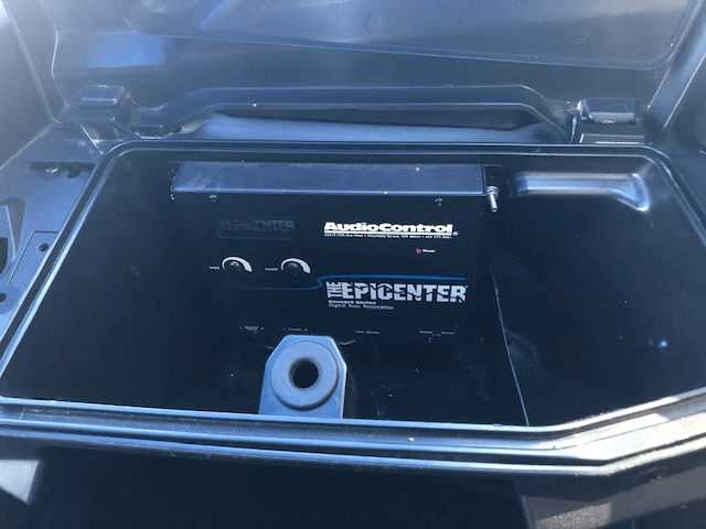 Car trunk with a black Epicenter audio component installed, showing silver accents and wires.