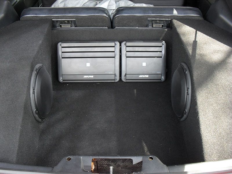 Car trunk with black carpet and two silver speakers mounted at the rear