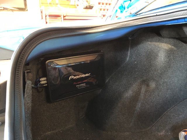 Open car trunk with a black Pioneer audio component mounted inside