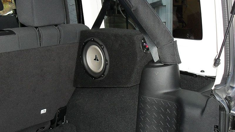 Car interior with a black speaker mounted in the rear side panel.