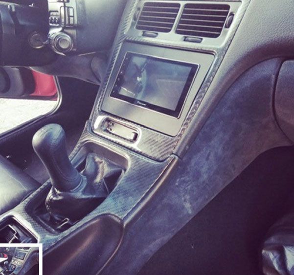 Car interior with manual gear shift and center console screen, black leather trim.