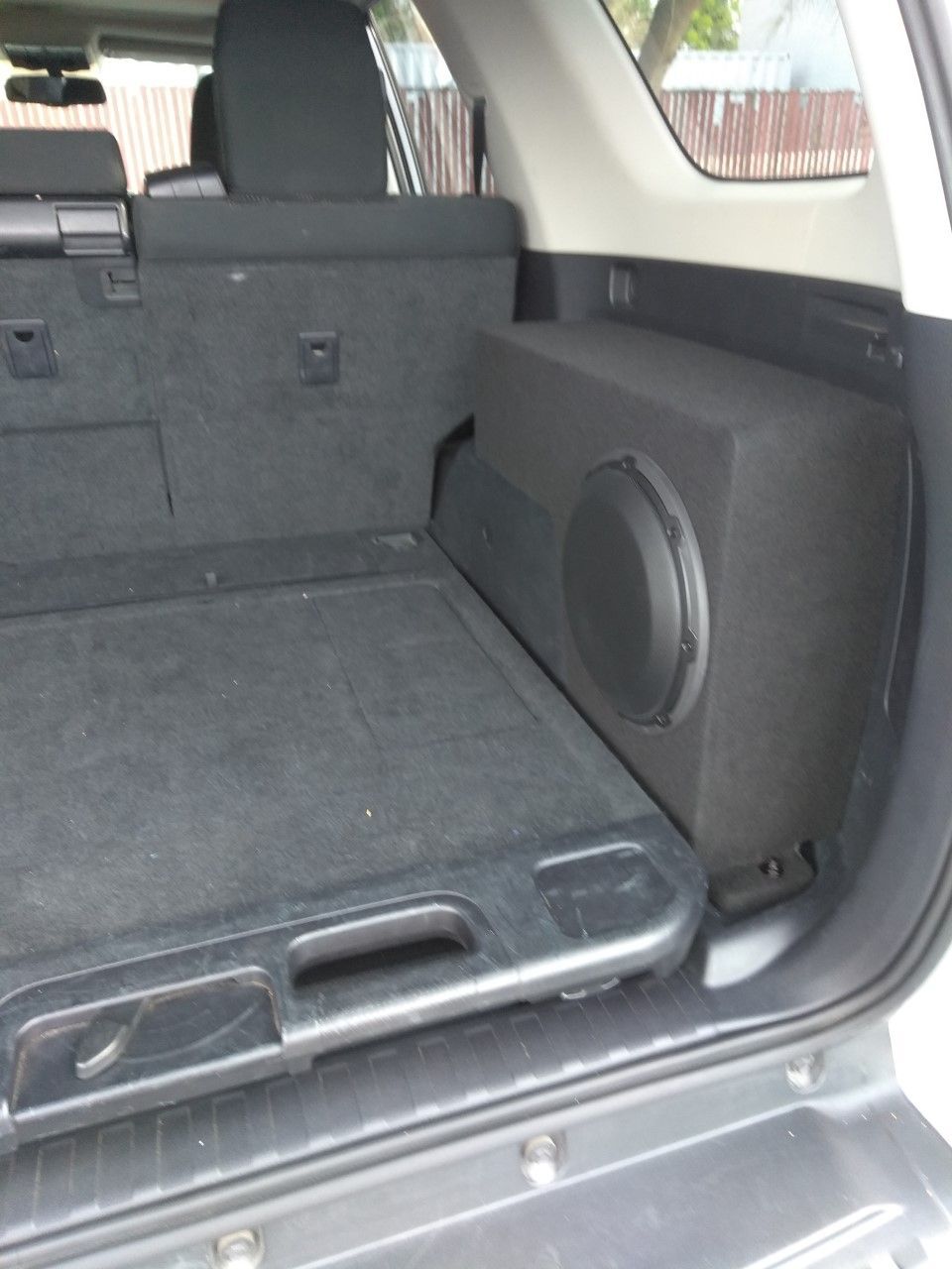 Car trunk interior with rear seats folded down and a speaker box on the right side.