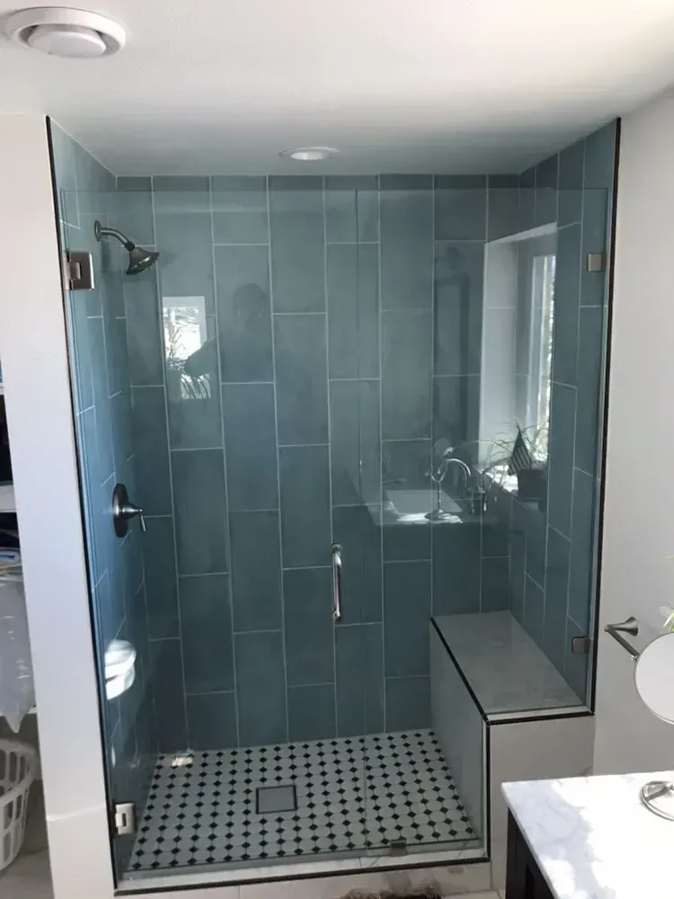 Modern blue-tiled walk-in shower with glass doors and mosaic floor tiles