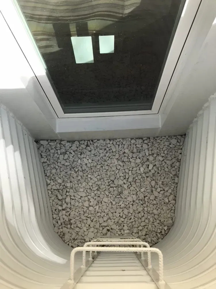 Top-down view through a skylight window into a small enclosed space with white walls and a patterned floor.