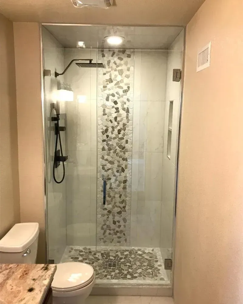 Bathroom with glass shower, gray tile accent, white toilet, and beige walls