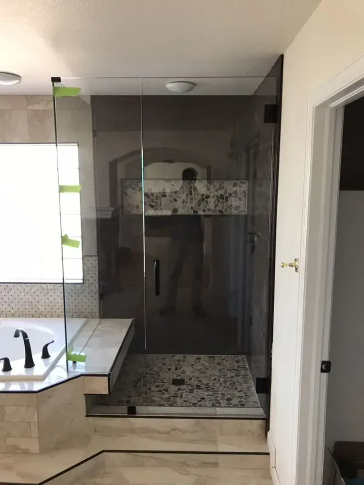 Modern bathroom with a glass shower enclosure, tiled floor, vanity sink, and open doorway.